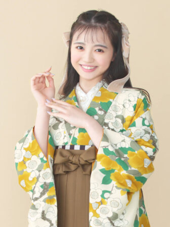 着物と袴のレンタルセット商品画像。袴はブラウン色。着物はカラシ色。梅椿柄のデザイン。上半身アップ画像。