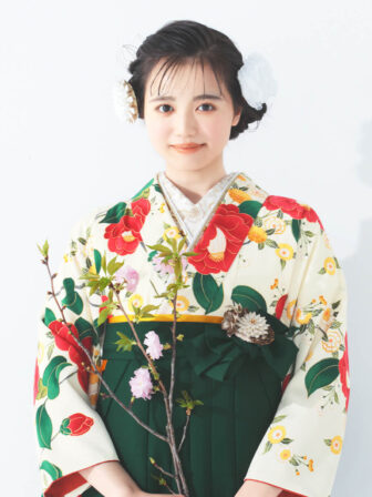 着物と袴のレンタルセット商品画像。袴は緑色。着物はオフ色。乙女椿柄のデザイン。上半身アップ画像。