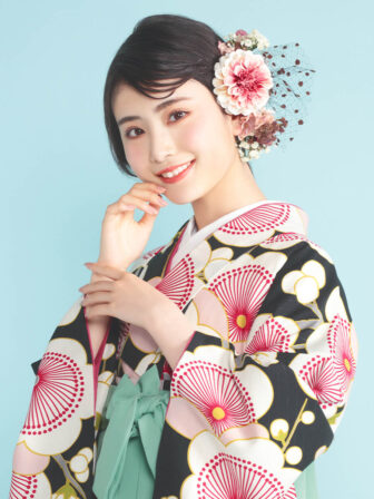 着物と袴のレンタルセット商品画像。袴はミントグリーン色。着物は黒色。梅柄のデザイン。上半身アップ画像。