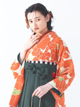 着物と袴のレンタルセット商品画像。袴はブルーグレー色。着物はオレンジ色。椿柄のデザイン。上半身アップ画像。